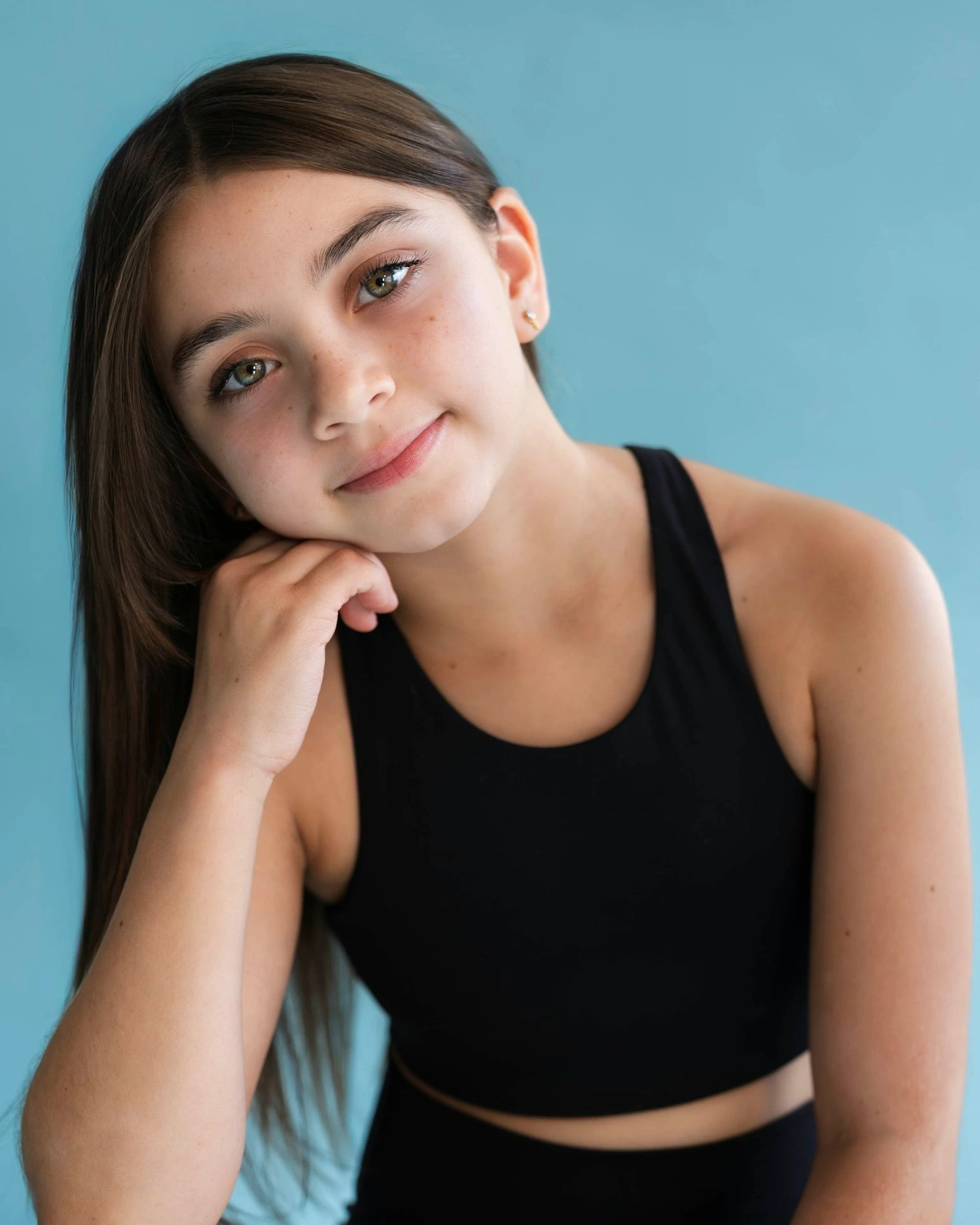 Girl in black top poses against blue background